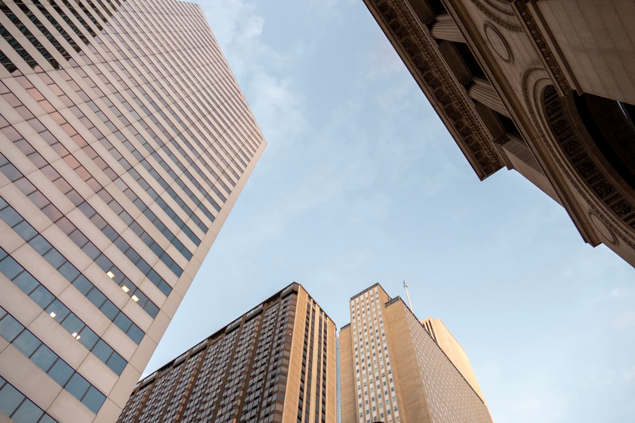 A low-angle view of several skyscrapers against a blue sky, highlighting their architectural details and height
