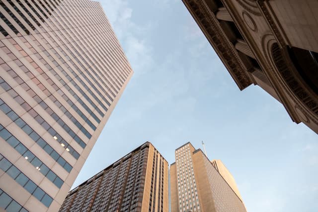 A low-angle view of several skyscrapers against a blue sky, highlighting their architectural details and height