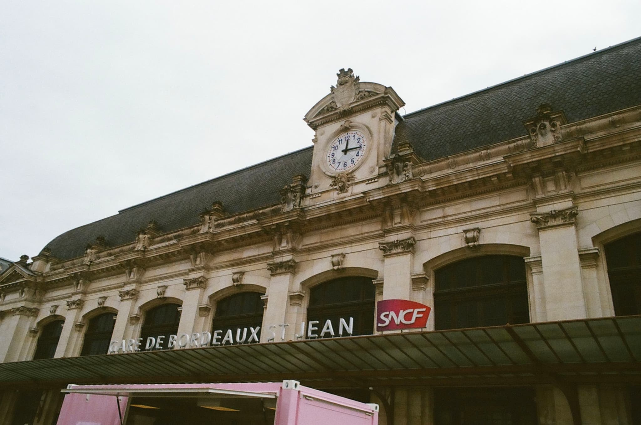 A historic train station facade with a clock and the sign Bordeaux Saint-Jean alongside the SNCF logo